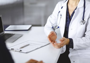 Bilinmeyen kadın-doktor, klinikteki dolapta birlikte otururken hastasıyla teşhisi hakkında konuşuyor. İşyerindeki doktor, yakın plan. Mükemmel bir tıbbi hizmet.