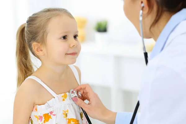 Docteur examinant une petite fille par stéthoscope. Heureux enfant patient souriant à l'inspection médicale habituelle. Médecine et concepts de santé — Photo