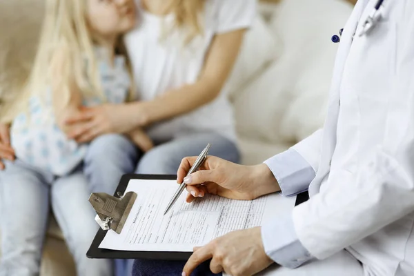 Dokter en patiënt. Kinderarts die klembord gebruikt terwijl ze het kleine meisje onderzoekt met haar moeder thuis. Ziek en ongelukkig kind bij medisch onderzoek. Geneesmiddelenconcept — Stockfoto