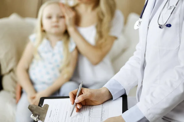 Dokter en patiënt. Kinderarts die klembord gebruikt terwijl ze het kleine meisje onderzoekt met haar moeder thuis. Ziek en ongelukkig kind bij medisch onderzoek. Geneesmiddelenconcept — Stockfoto