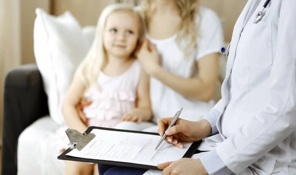 Dokter en patiënt. Kinderarts die klembord gebruikt terwijl ze het kleine meisje onderzoekt met haar moeder thuis. Ziek en ongelukkig kind bij medisch onderzoek. Geneesmiddelenconcept — Stockfoto