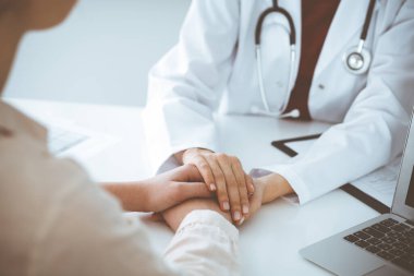 Kadın hastasına güvence veren kimliği belirsiz kadın doktorun elleri, yakın plan. Tıp konsepti