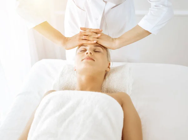 Güzel sarışın kadın güneşli spa merkezinde kapalı gözlerle yüz masajından hoşlanıyor. Tıp ve güzellik kavramlarında rahatlatıcı tedavi — Stok fotoğraf