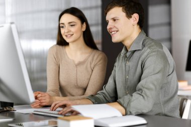 Gülümseyen genç işadamları ve programcılar modern bir ofiste birlikte otururken bilgisayardaki bazı verileri kontrol ediyorlar. İnsanoğluna odaklan. Başarılı iş kurma kavramı