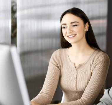 Yeşil gömlekli arkadaş canlısı genç işadamı ve programcı, modern bir ofiste masa başında bayan bir meslektaşla birlikte otururken bilgisayar üzerinde çalışıyor. Kadınlara odaklan. Başarılı olma kavramı