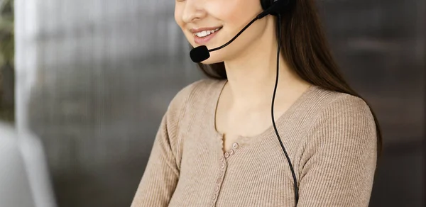 Two young smiling people in headsets are talking to the clients, while sitting at the desk in a modern office. Call center operators at work — Stock Photo, Image