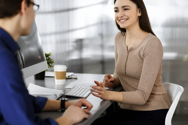 Los jóvenes empresarios están hablando entre sí, mientras están sentados en el escritorio de una oficina moderna. Concéntrate en mujer. Concepto de éxito empresarial — Foto de Stock