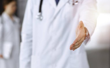 Bilinmeyen bir adam-doktor ayakta duruyor ve modern klinikte yardım eli uzatıyor. Kadın meslektaşının doktor geçmişinde acelesi var. Tıp konsepti