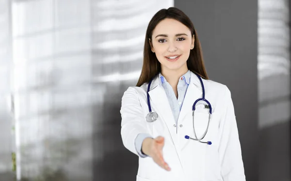 La joven doctora está ofreciendo su ayuda para estrechar la mano o salvar la vida. El médico está listo para ayudar a los pacientes. Ayuda médica, seguro médico, el mejor tratamiento de enfermedades y medicamentos —  Fotos de Stock