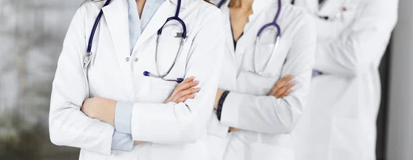 Grupp av professionella läkare står som ett team med armarna korsade på kliniken. Medicinskt koncept under Coronavirus pandemi — Stockfoto