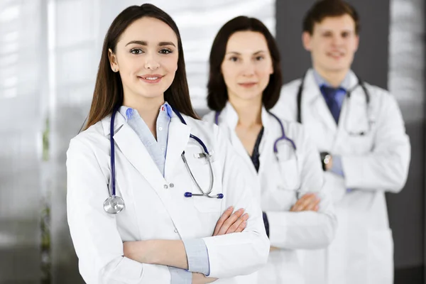 Group of young professional doctors is standing as a team with arms crossed in a hospital office and is ready to help patients. Medical help, insurance in health care, best disease treatment and