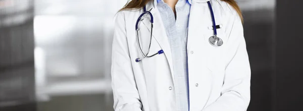 Nieznana młoda kobieta doktor stoi z rękami skrzyżowanymi w klinice. Koncepcja medycyny podczas pandemii koronawirusowej — Zdjęcie stockowe