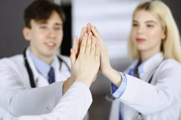 Skupina moderních lékařů se drží za ruce a dává si pět jako znamení silné týmové práce a jsou připraveni pomáhat pacientům. Koronavirus měření a medicína koncept — Stock fotografie