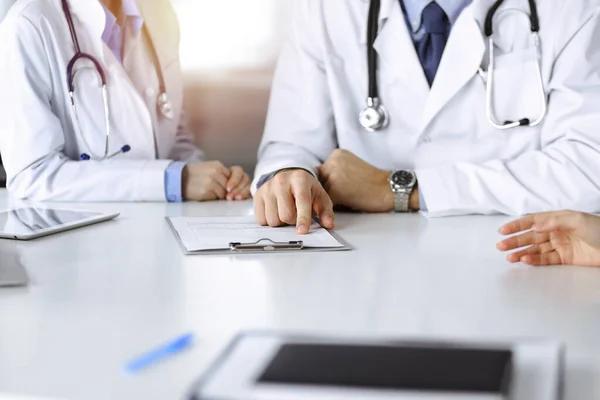 Médico masculino desconocido escuchando a su paciente mujer mientras está sentado en una clínica soleada. Concepto de medicina durante la pandemia del Coronavirus. Covid 2019 — Foto de Stock