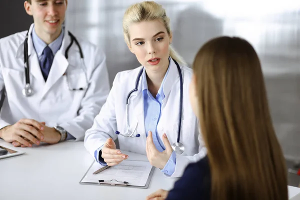 Mulher-médico com colega do sexo masculino estão consultando mulher paciente enquanto sentado na mesa na clínica moderna. Serviço médico perfeito, conceito de medicina — Fotografia de Stock