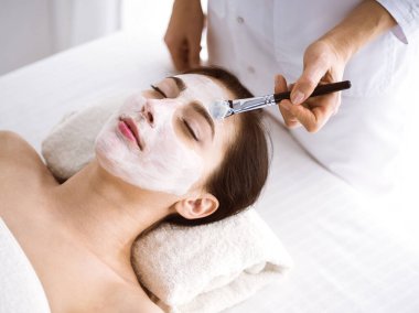 Güzel esmer kadın kozmetik maske takmaktan zevk alıyor. Rahat ve bisküvi dolu. Tıp ve kaplıca merkezi kavramlarında rahatlatıcı tedavi