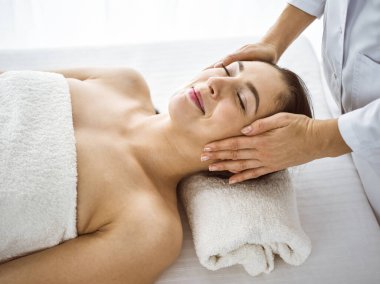 Güzel esmer kadın rahat ve bisküvi dolu yüz masajından hoşlanıyor. Tıp ve kaplıca merkezi kavramlarında rahatlatıcı tedavi