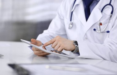 Bilinmeyen erkek doktor klinikteki tablet bilgisayarla yakın planda çalışıyor. İşteki genç doktor. Mükemmel sağlık hizmeti, tıp konsepti
