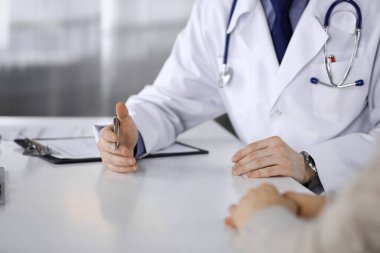 Bilinmeyen erkek doktor ve hasta kadın klinikte oturup dosya kullanırken bir şey tartışıyorlar. Hastanedeki en iyi sağlık hizmeti, ilaç, salgın durdurma.