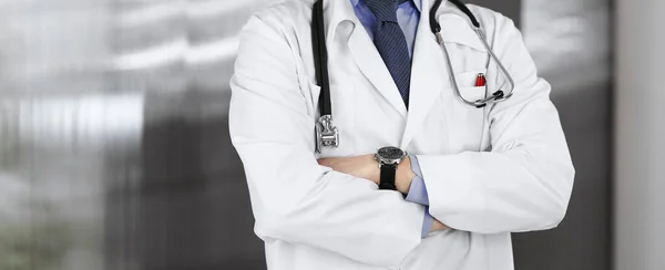 Unknown male doctor standing with arms crossed in clinic. Medicine concept during Coronavirus pandemic — Stock Photo, Image