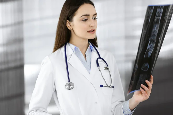 Professionell ung kvinna-läkare tittar på hennes patienter roentgenogram. Läkare på ett klinikkontor. Medicinskt koncept — Stockfoto