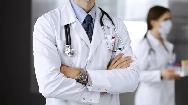 Unknown male doctor in protective mask standing with arms crossed in clinic. Medicine concept during Coronavirus pandemic. Covid 2019 — Stock Photo, Image