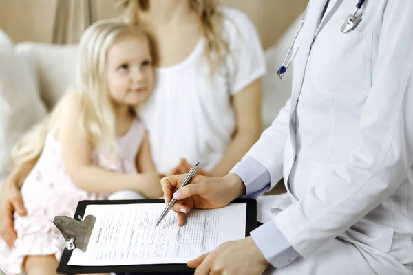 医者と患者だ。小児科医は、自宅で母親と一緒に小さな女の子を検討しながら、クリップボードを使用して.医学試験で病気で不幸な子供。医学の概念 — ストック写真