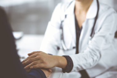 Bilinmeyen kadın doktor, kadın hastasına güvence veriyor, yakın plan. Doktor bir kadına danışmanlık yapıyor ve tavsiyelerde bulunuyor. Tıbbi ahlak ve güven kavramları. Tıpta empati