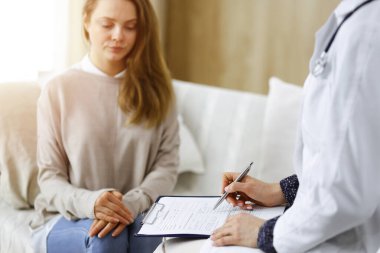 Kadın-doktor ve hasta yakın plan çekimleri. İçeride otururken sağlık muayenesini tartışıyorlar. Coronavirus salgını ve kendini izolasyon karantinası sırasında evde kal. Covid 2019