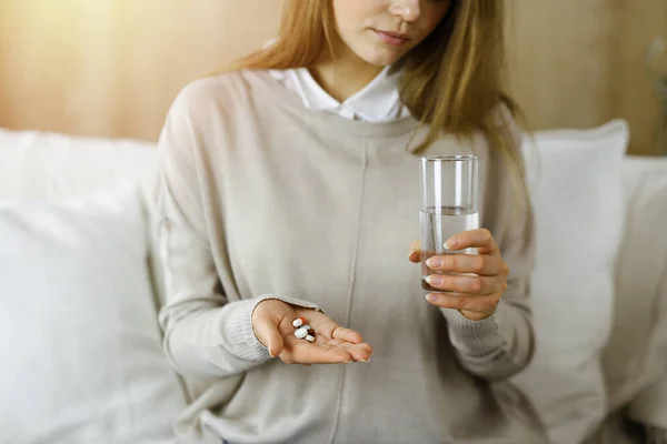 Close-up woman holding pills time to take medications, cure for headache. Medicine concept during self isolation and Coronavirus pandemic