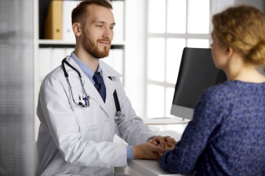 Dost canlısı kızıl sakallı doktor, kadın hastasına güven veriyor. Tıp etiği ve güven kavramı, tıp teması