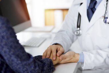 Dost canlısı kızıl sakallı doktor, kadın hastasına güvence veriyor, yakın plan. Tıp etiği ve güven kavramı, tıp teması