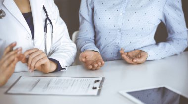 Bilinmeyen kadın. Doktor, klinikteki dolapta birlikte otururken hastasını dinliyor. Steteskoplu kadın doktor panoya yazı yazıyor, kapat. Mükemmel sağlık.