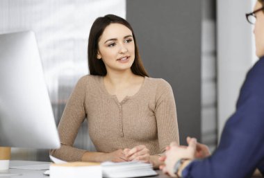 Genç iş adamları modern bir ofiste masada otururken birbirleriyle konuşuyorlar. İş başarısı kavramı