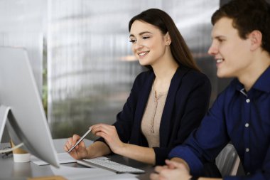 Çalışma masasında birlikte otururken iş yerindeki genç ve dost canlısı iş adamları. Kadınlara odaklan. Modern bir ofiste vesikalık ya da iş portresi