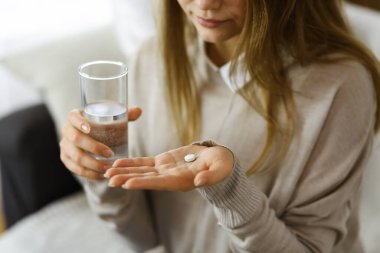 Kapalı çekim kadın ilaç almak için zaman tutuyor, baş ağrısı için tedavi, yüksek tansiyon veya kolesterol seviyesinde ağrı kesici ilaçlar. Coronavirus salgını ve kendi kendine olan konseptinde kal.