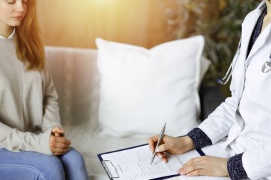 Kadın-doktor ve hasta yakın plan çekimleri. İçeride otururken sağlık muayenesini tartışıyorlar. Coronavirus salgını ve kendini izolasyon karantinası sırasında evde kal. Covid 2019