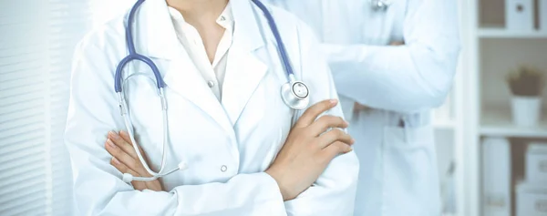 Άγνωστη γυναίκα-γιατρός στέκεται ευθεία με τα χέρια σταυρωμένα στην κλινική, κοντινό πλάνο. Ιατρική ομάδα έτοιμη να σταματήσει την πανδημία του κορωναϊού. Έννοια ιατρικής — Φωτογραφία Αρχείου