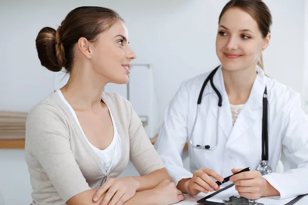 Médecin et patient sont assis et discutent des résultats des examens de santé dans le bureau de la clinique. Soins de santé, médecine et bonnes nouvelles concepts — Photo