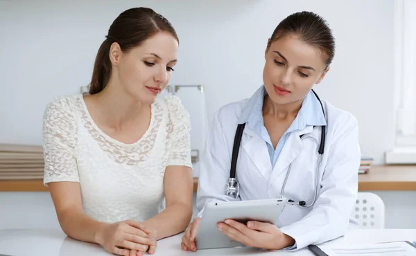 의사와 환자들은 태블릿 컴퓨터를 사용하면서 앉아서 건강 검진 결과에 대해 논의하고 있다. 건강 관리, 의약품 및 좋은 소식 개념 — 스톡 사진