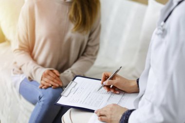 Kadın-doktor ve hasta yakın plan çekimleri. İçeride otururken sağlık muayenesini tartışıyorlar. Coronavirus salgını ve kendini izolasyon karantinası sırasında evde kal. Covid 2019