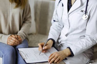 Bilinmeyen kadın doktor ve hasta içeride otururken sağlık muayenesini tartışıyorlar. Coronavirus salgını ve kendini izolasyon karantinası süresince evde kal