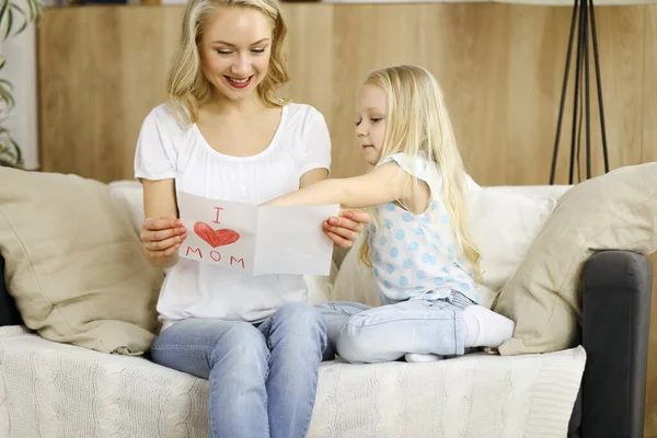 Glücklicher Muttertag. Die Tochter gratuliert der Mutter und überreicht ihr eine Postkarte mit Herzzeichnung. Familien- und Kindheitskonzepte — Stockfoto