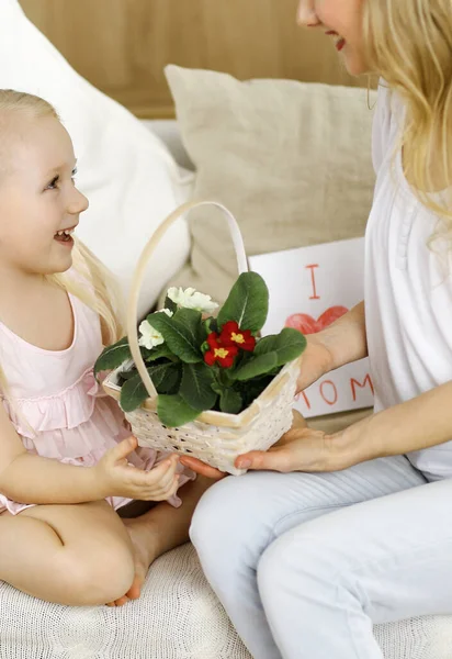 Bonne fête des mères Enfant fille félicite maman et donne son panier de fleurs de printemps et carte postale avec dessin au coeur. Concepts famille et enfance — Photo
