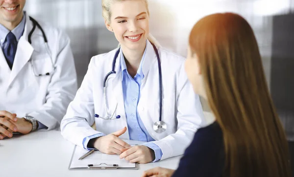 Mulher-médico com colega do sexo masculino estão consultando mulher paciente enquanto sentado na mesa na clínica moderna. Serviço médico perfeito, conceito de medicina — Fotografia de Stock