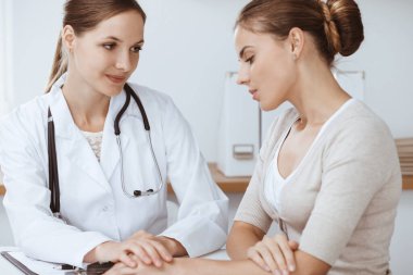 Doktor ve hasta klinikte oturup sağlık muayenesi sonuçlarını tartışıyorlar. Sağlık, ilaç ve iyi haber kavramları