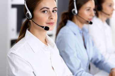 Merkezi ara. Bir grup operatör iş başında. Kulaklık takmış güzel bir iş kadınıyla