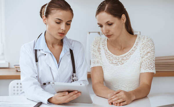 Врач и пациент сидят и обсуждают результаты обследования здоровья во время использования планшетного компьютера. Здравоохранение, медицина и хорошие новости