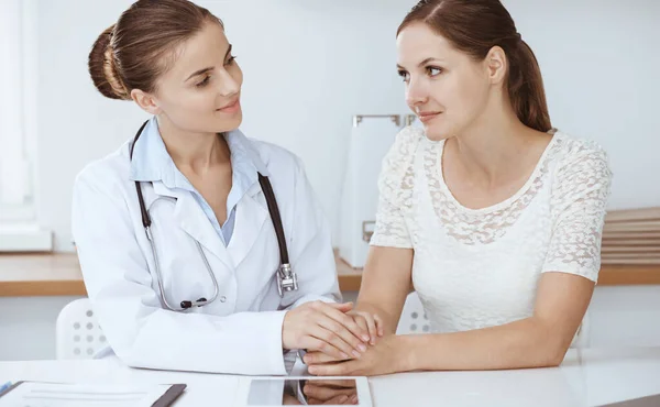 La doctora tranquiliza a su paciente mientras está sentada en el escritorio. Concepto de medicina — Foto de Stock