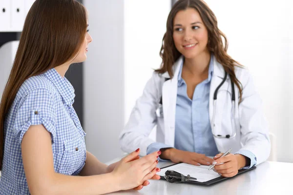 Médico y paciente feliz hablando mientras está sentado en el escritorio. El médico o terapeuta discute el estilo de vida saludable. Concepto de atención de salud, medicina y servicio al paciente — Foto de Stock